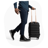 Model walking in airport with suitcase, wearing black and white amberjack chelsea boots