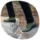 model walking on rocks wearing The Boot in Olive green Nubuck