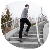model running up stairs wearing dark pants and sweater with The Boot in Steel Nubuck